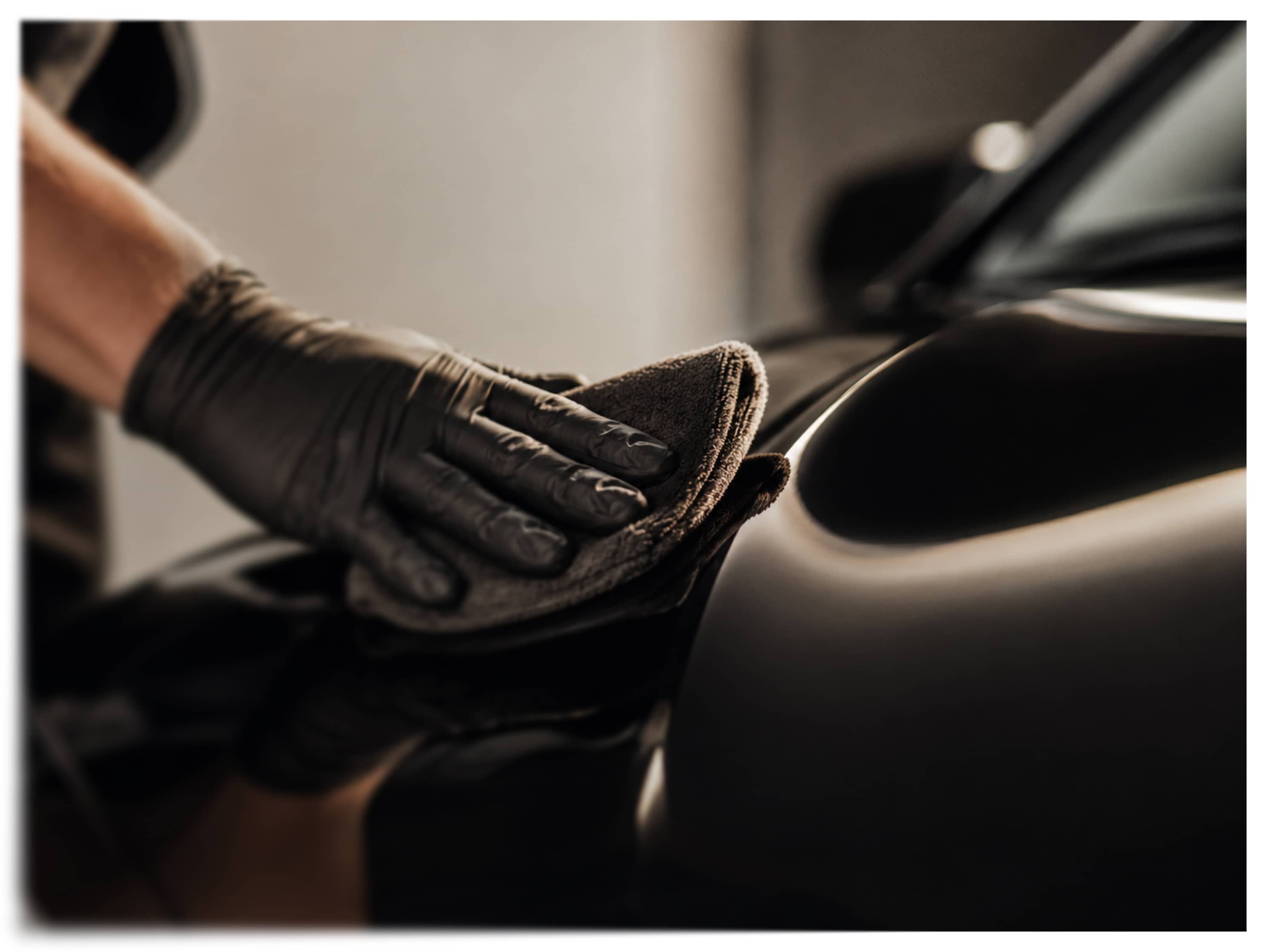 Gloved hand meticulously applying ceramic coating to a luxury car