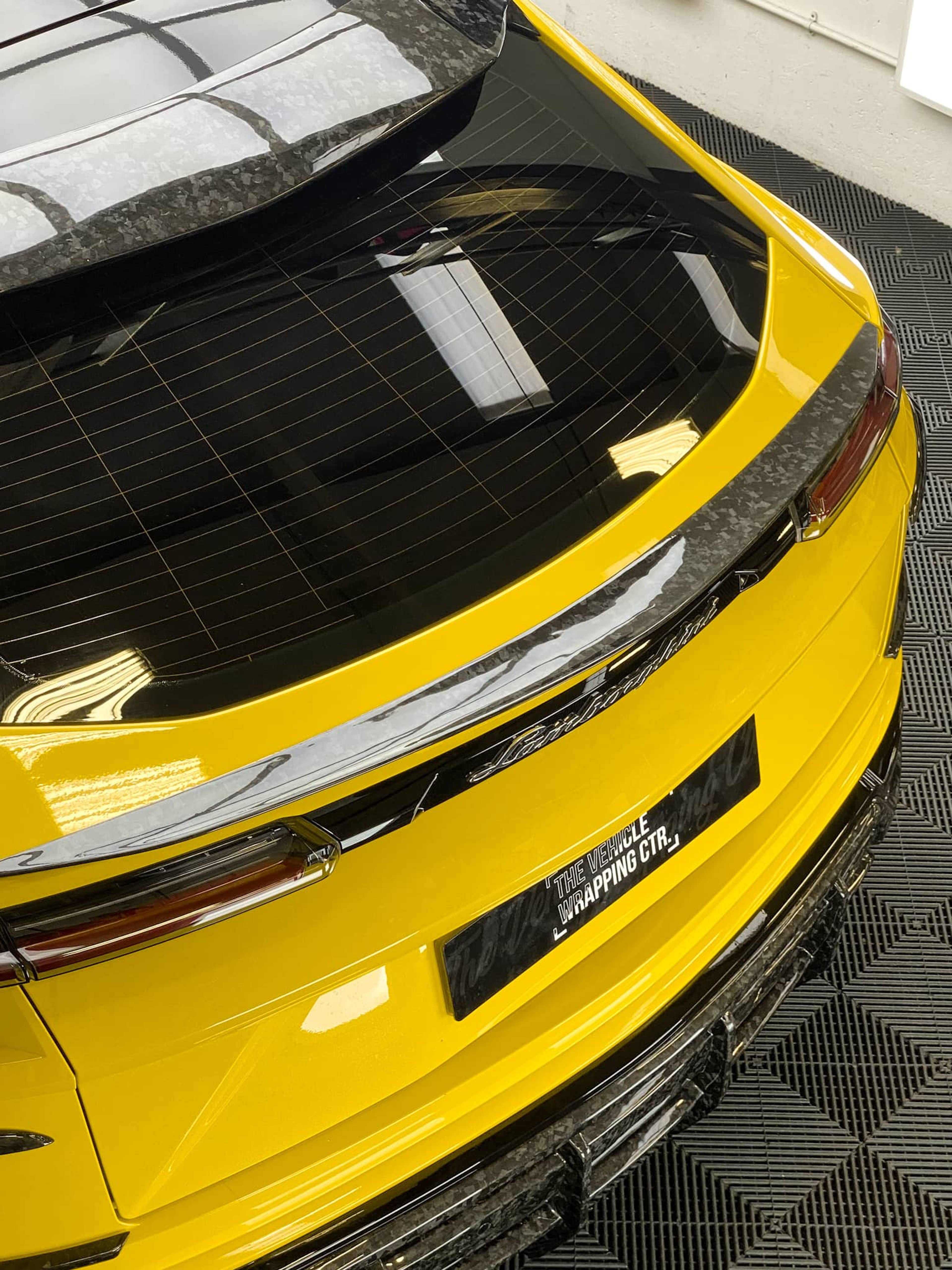 A custom Forge Lamborghini Urus parked on a bright workshop floor, viewed from above at the rear.