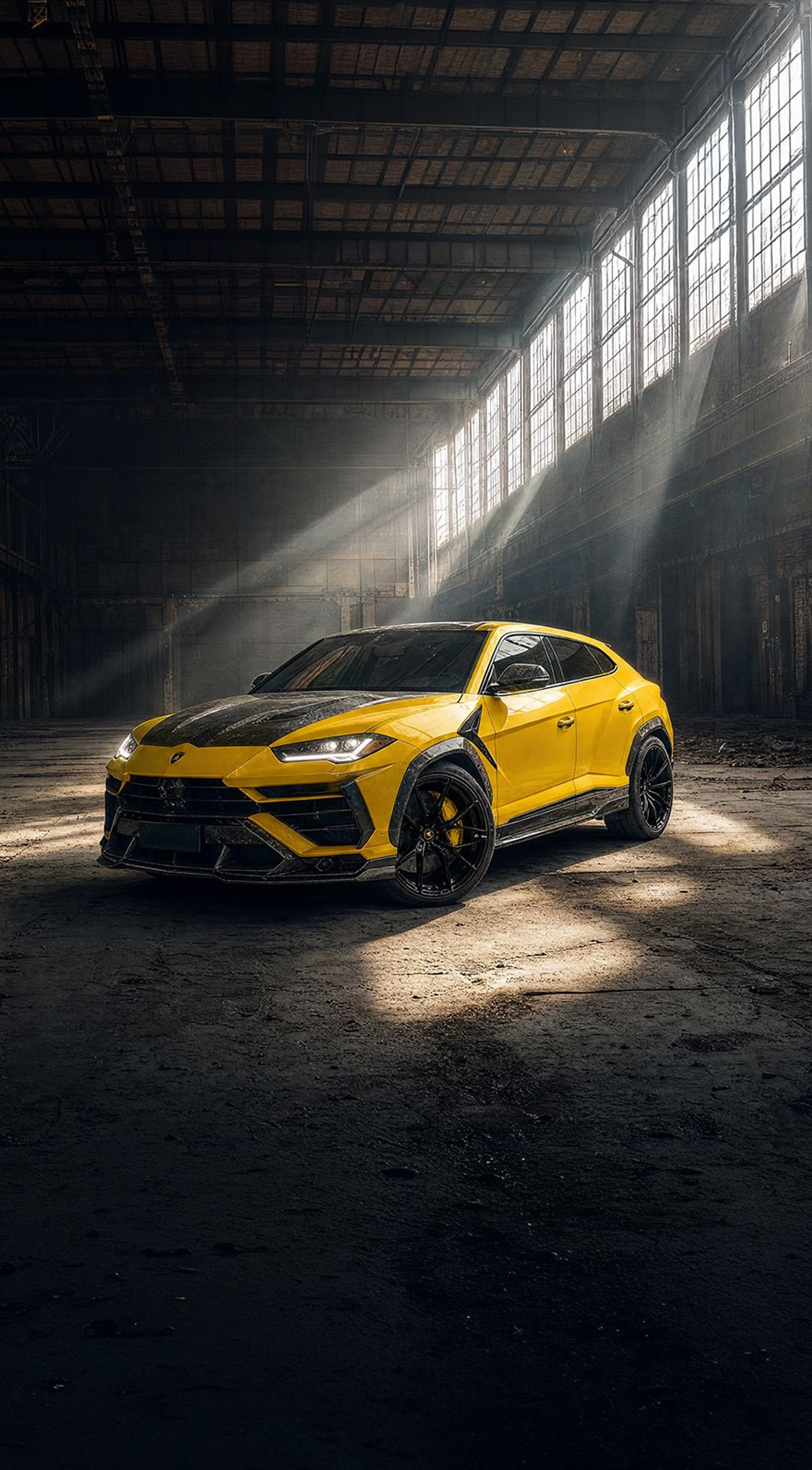 A yellow custom Forge Lamborghini Urus parked inside a rustic, sunlit warehouse.