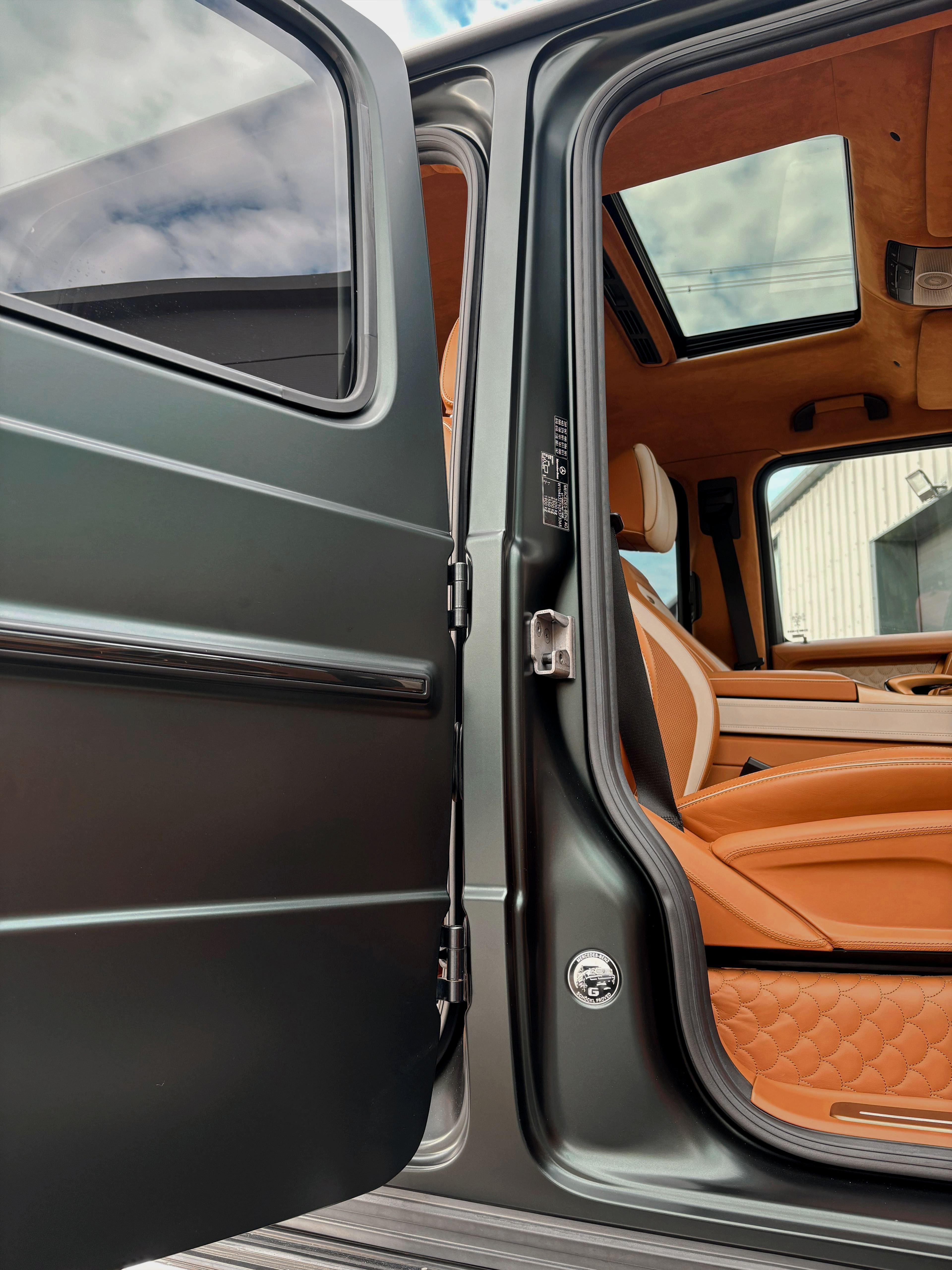 An open door of a custom Forge Mercedes G63 reveals a tan leather interior and a sunroof.