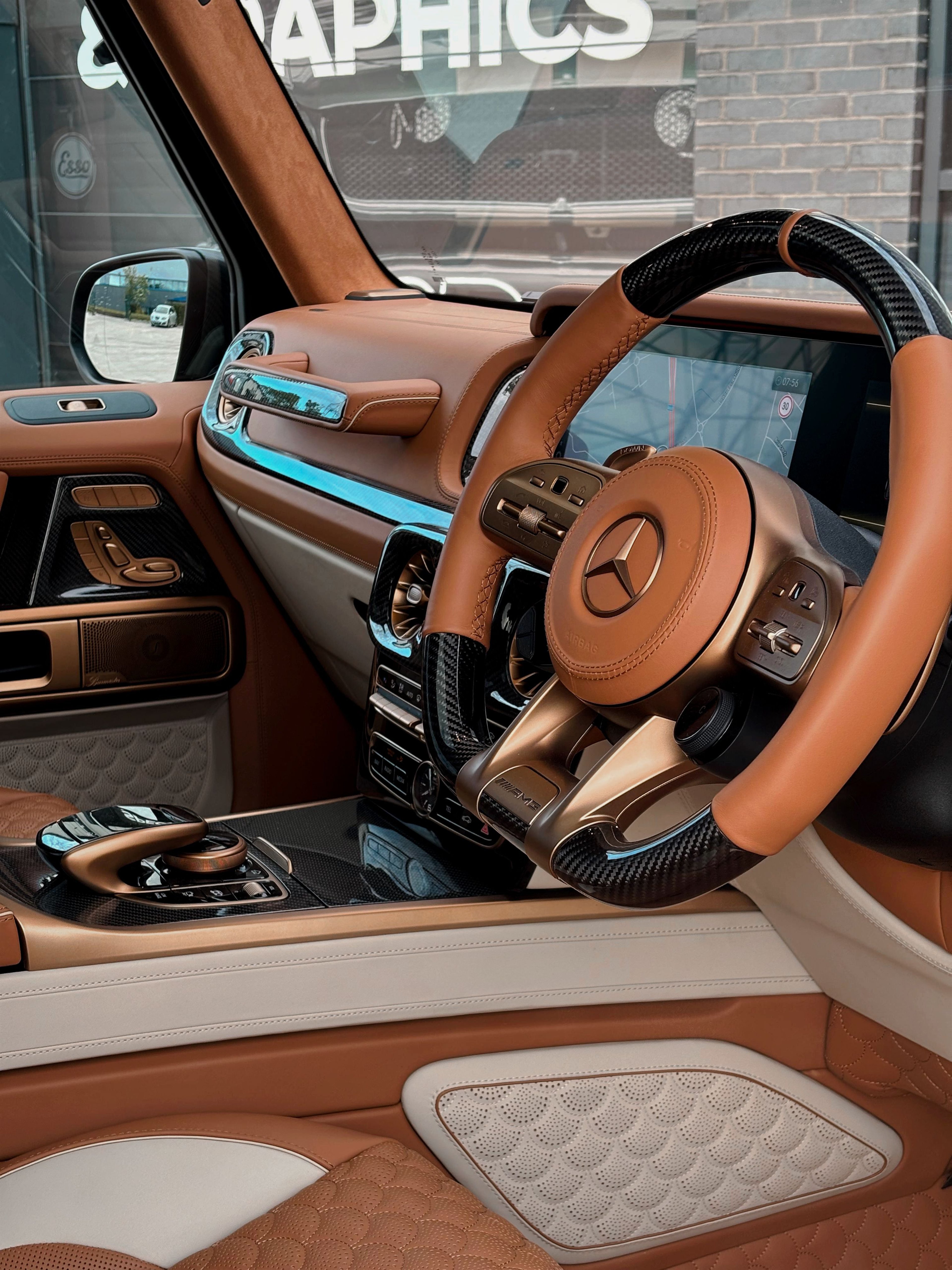 A custom Forge Mercedes G63 interior with brown leather and carbon fiber steering wheel details.