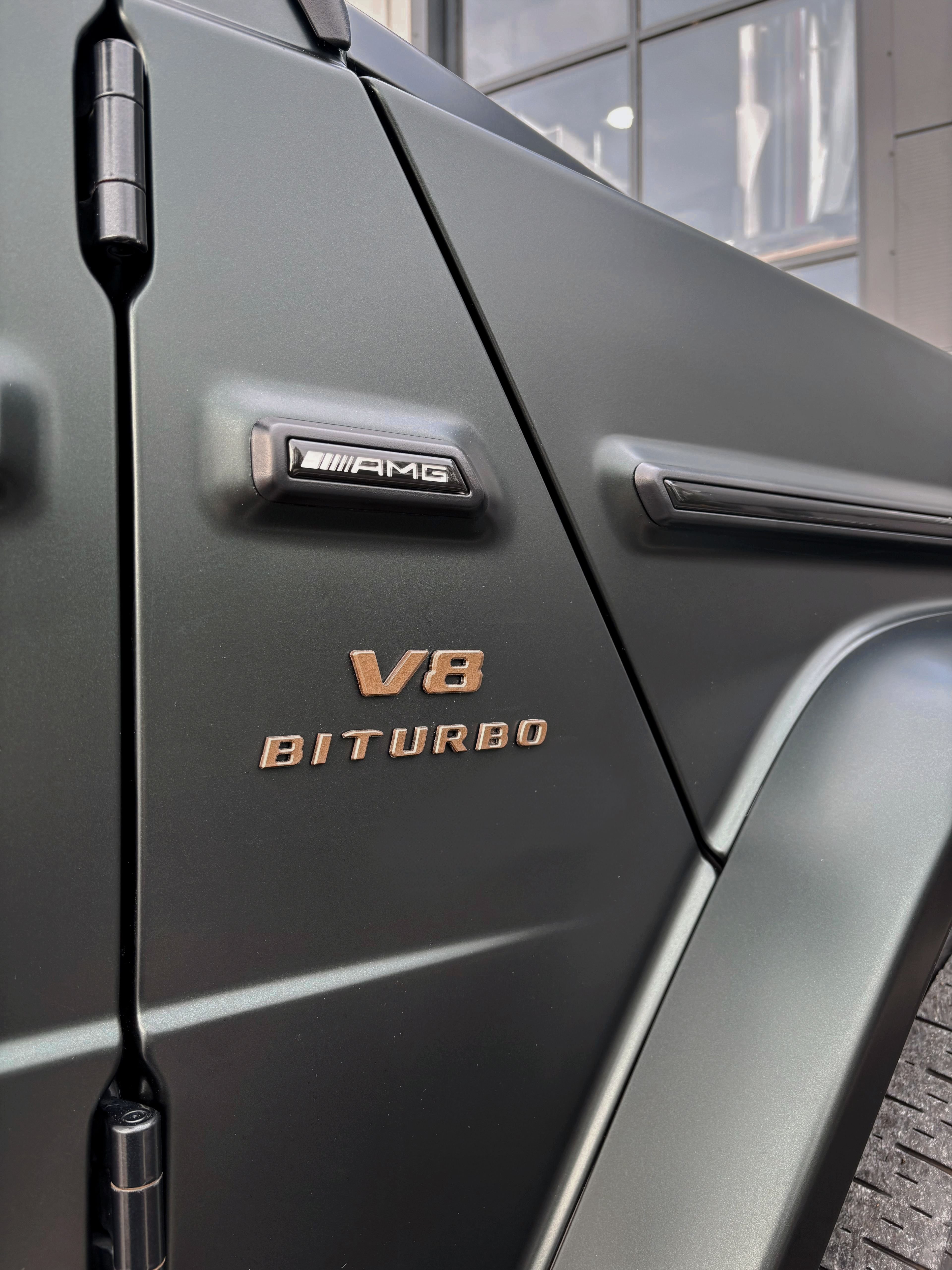 A close-up view of the matte paint and V8 Biturbo badging on a custom Forge Mercedes G63 parked outdoors.